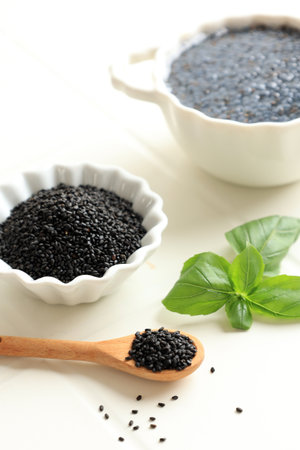 Organic Basil Seeds in Wooden Spoon and Small Bowl, with Soaked Basil Seeds on the Background. Superfood, Ocimum basilicum.の写真素材