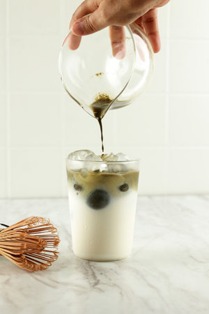 Matcha Tea is Poured in Iced Milk. Healthy Vegan Drink Matcha Latteの写真素材