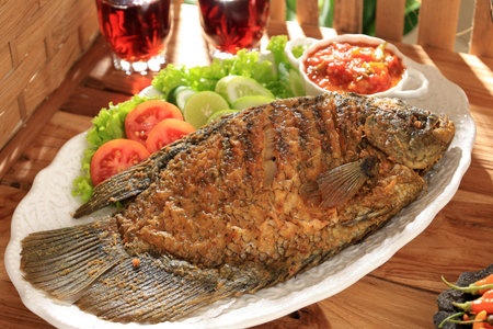 Close Up Ikan Gurame Goreng, Deep Fried Gourami Served with Indonesian Sambal Spicy Sauce and Lettuce and Tomatoの写真素材