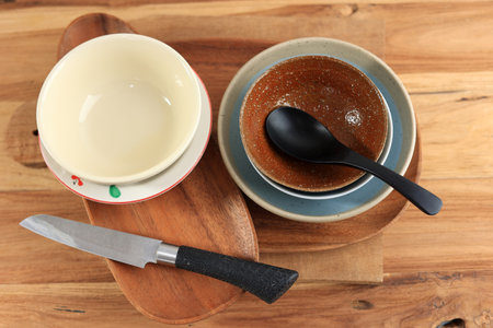 Ceramic Bowl, Plate, Wooden Plate, Knife, Spoon, and other Kitchen Equipment on Wooden Tableの写真素材