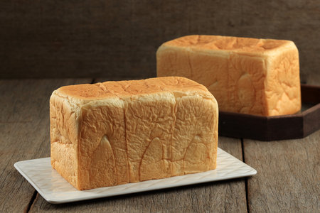 Japanese Shokupan Bread Loaf on White Plate above Rustic Wooden Table
