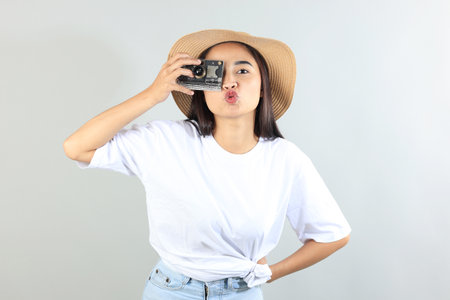 Asian Female Traveler Wearing Summer Hat and Holding Camera While Traveling, Isolated on grey Backgroundの写真素材