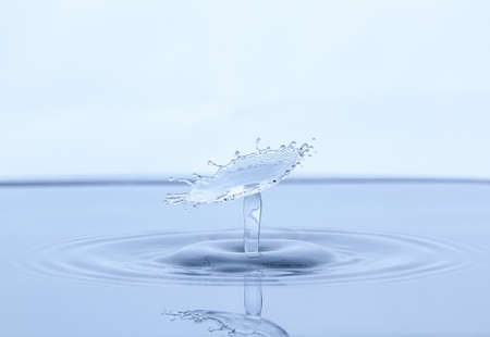 Splash and umbrella on white background. Reflection on the surface of the water.の写真素材