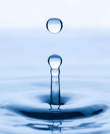 Splash and a ball of water on a blue background. Reflection on the surface of the water.の写真素材