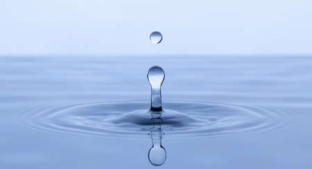 Splash and a ball of water on a blue background. Reflection on the surface of the water.の写真素材