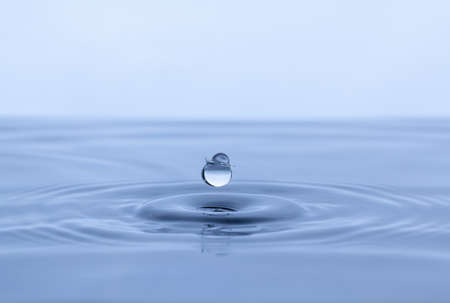 Splash and a ball of water on a blue background. Reflection on the surface of the water.の写真素材