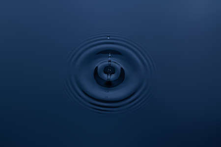 Splash and a ball of water on a blue background. Reflection on the surface of the water.