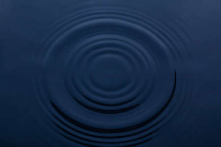 Splash and circle of water on a blue background. Reflection on the surface of the water.の写真素材