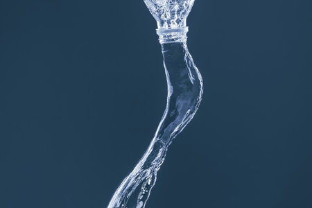 Splash of water from a bottle on a blue background. Reflection on the surface of the water.