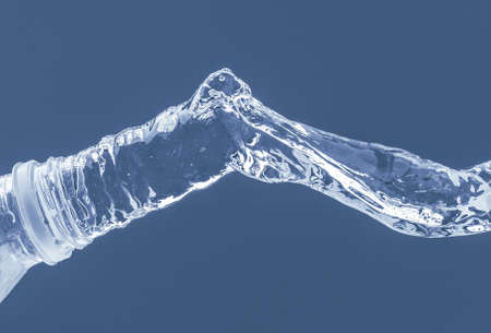 Splash of water from a bottle on a blue background. Reflection on the surface of the water.の写真素材