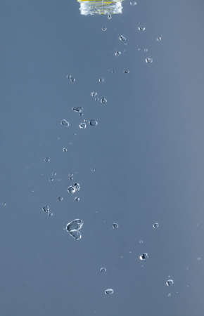 Splash of water from a bottle on a blue background. Reflection on the surface of the water.の写真素材