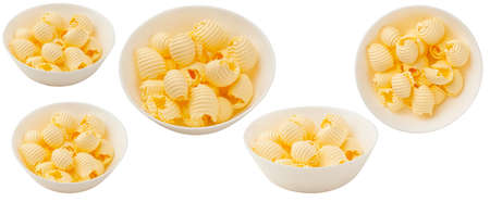 Butter curls rolled up isolated on white background. A set of pieces of butter in a bowl.の写真素材