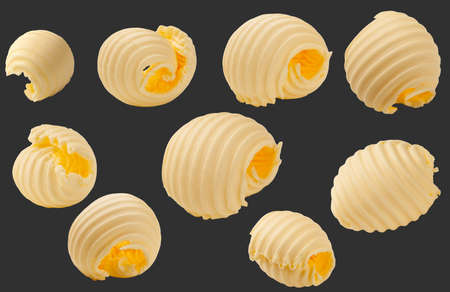 Butter curls rolled up isolated on black background. Set of pieces of butter.の写真素材