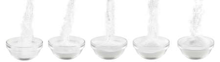 Soda in a glass bowl. Soda, flour, salt or sugar is poured into a glass container. Five plates with white powder on a white background.の写真素材