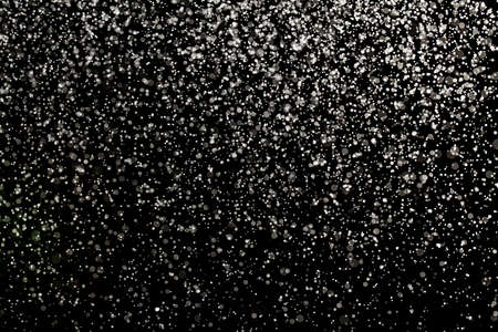 Sprayed water. Small droplets of water in the air. Lots of water drops, isolated on black background.の写真素材