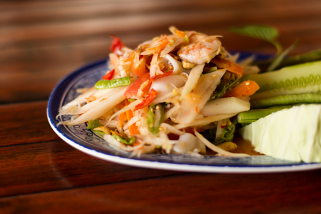 spicy papaya salad (SOM TAM THAI) Thai Cuisine in white plate on wooden tableの写真素材