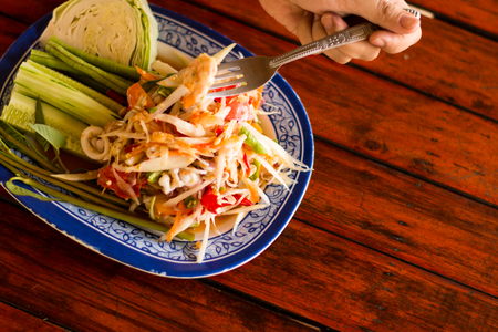 spicy papaya salad (SOM TAM THAI) Thai Cuisine in white plate on wooden tableの写真素材