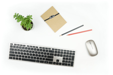 White office desk with computer gadgets, flower and notepad with pencils. Top view with flat lay.