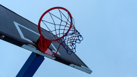 Basketball shabby backboard with a red basketball hoop in cloudy weather