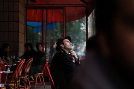 Paris, France, November 1, 2013: Man in hat looking towards the horizon inside a bar crowded with peopleのeditorial素材