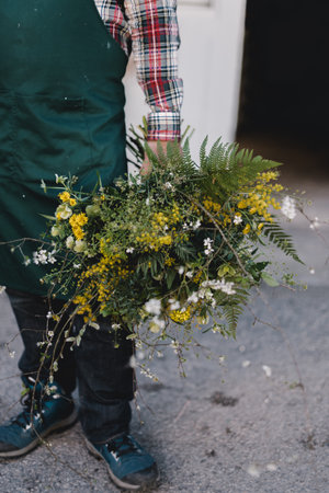 Vertical photo with selective focus on a bunch of wild flowers in the hand of a gardener.の写真素材