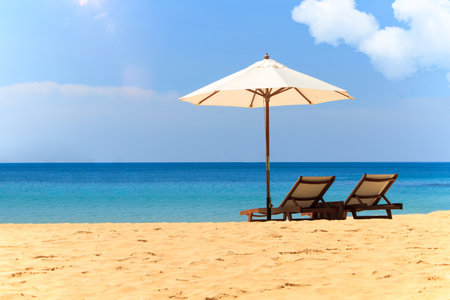 Beach chairs and umbrella on beautiful tropical beach with blue sky backgroundの写真素材
