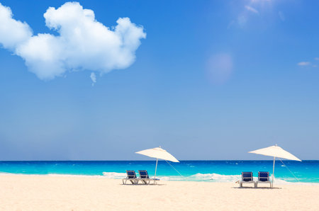 Beach chairs and umbrella on a tropical beach with blue sky backgroundの写真素材