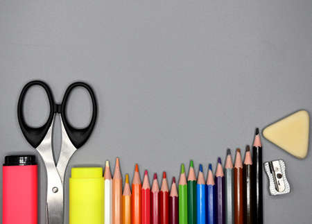 School supplies, colored pencils, pencil sharpener, eraser, markers and scissors at the bottom, gray...
