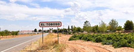 Welcome sign to El Toboso next to the road and vineyards.の写真素材