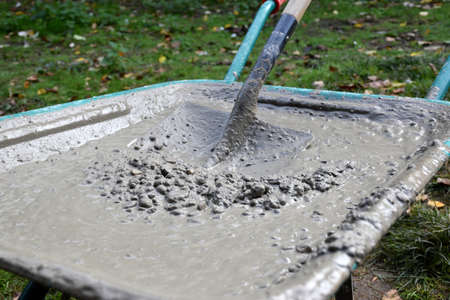 Wheelbarrow full of concrete and nailed metal and wood shovel.の写真素材