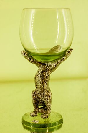 A decorated wine glass with a lemon yellow hue. The handle is made of a coated metal.の写真素材