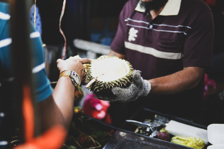 A seller showing the durian fruit to tourist. Durian - an exotic fruit with a very unpleasant and...