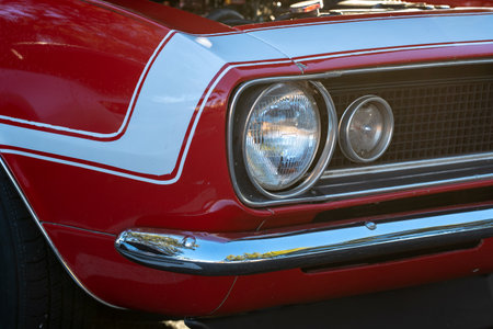 A closeup of the headlight and radiator of a red vintage car