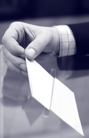 Image of a ballot box and hand putting a blank ballot inside,elections, voting conceptの写真素材