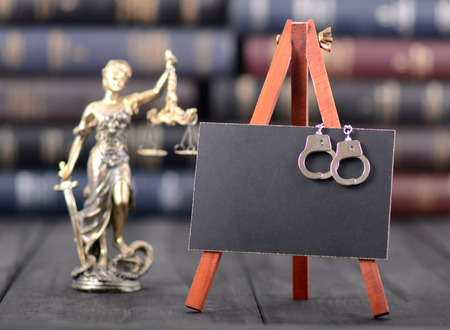 Blackboard, handcuffs, Lady Justice on the wooden background