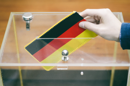 Man inserting Flag of Germany into ballot box, voting and elections in Germany.の写真素材