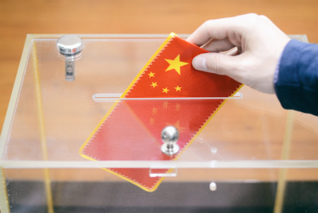 Man inserting Flag of China into ballot box, voting and elections in China.の写真素材