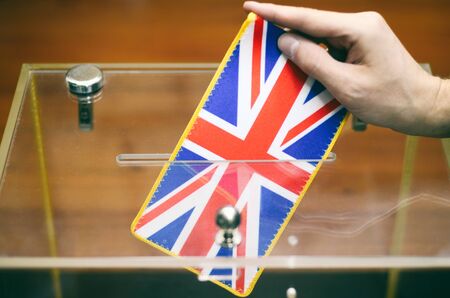 Man inserting United Kingdom flag into ballot box, voting and elections in United Kingdom.