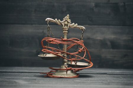 Scales of Justice and barbed wire on a black wooden background, Compromised Rule of Law, Weakness of...