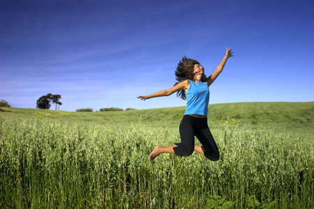  Young active woman jumping on a green fieldの写真素材