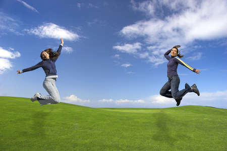 Girls jumping on the green fieldの写真素材