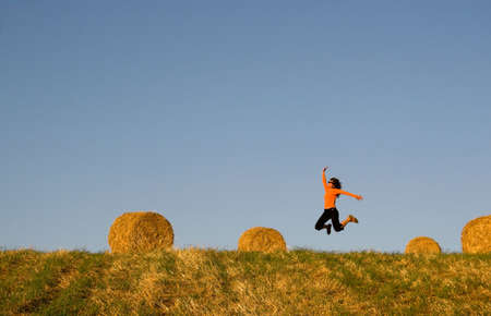 Woman jumping in a hay bales fieldの写真素材