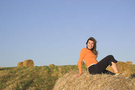 Beautiful woman in a field with hay balesの写真素材