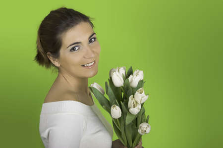 Beautiful woman on a green background with white tulips on the handsの写真素材