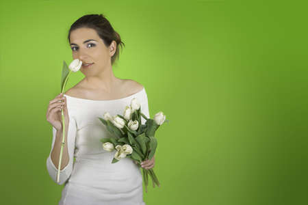 Beautiful woman on a green background smeeling a tulipの写真素材