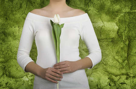 Woman with white tulips on is hands on a green wallの写真素材