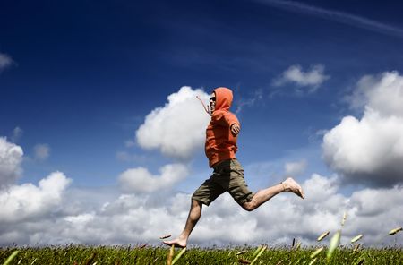 Man running and jumping on a green meadowの写真素材