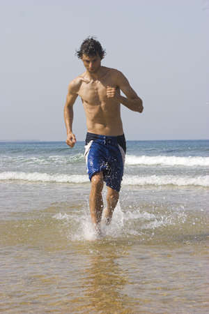 Picture of a young man running on the beachの写真素材