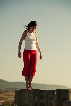 Young woman walking on a wood fenceの写真素材