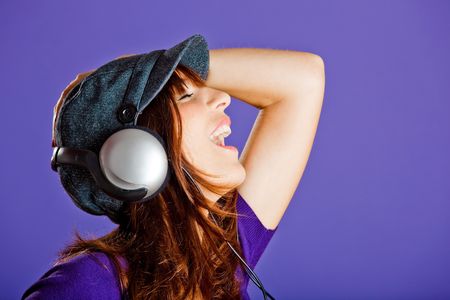 Beautiful and happy young woman listen music with headphones, over a violet backgroundの写真素材